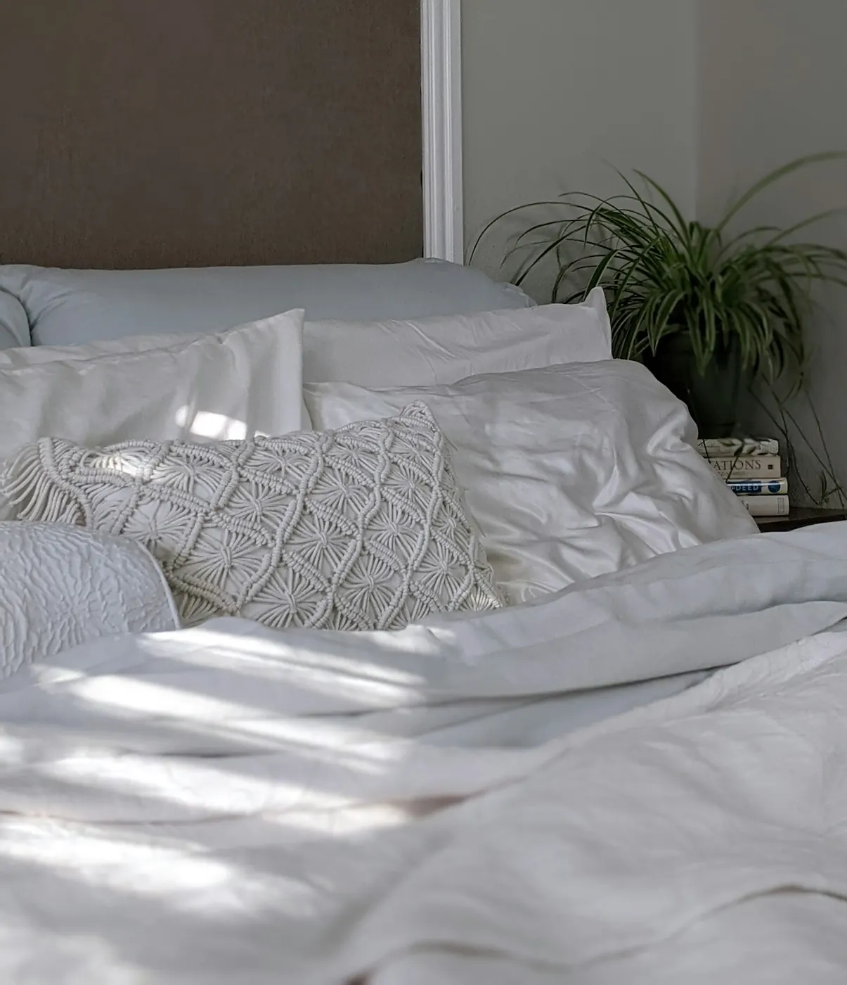 White and grey cotton bed linen with textured cushions in a bedroom
