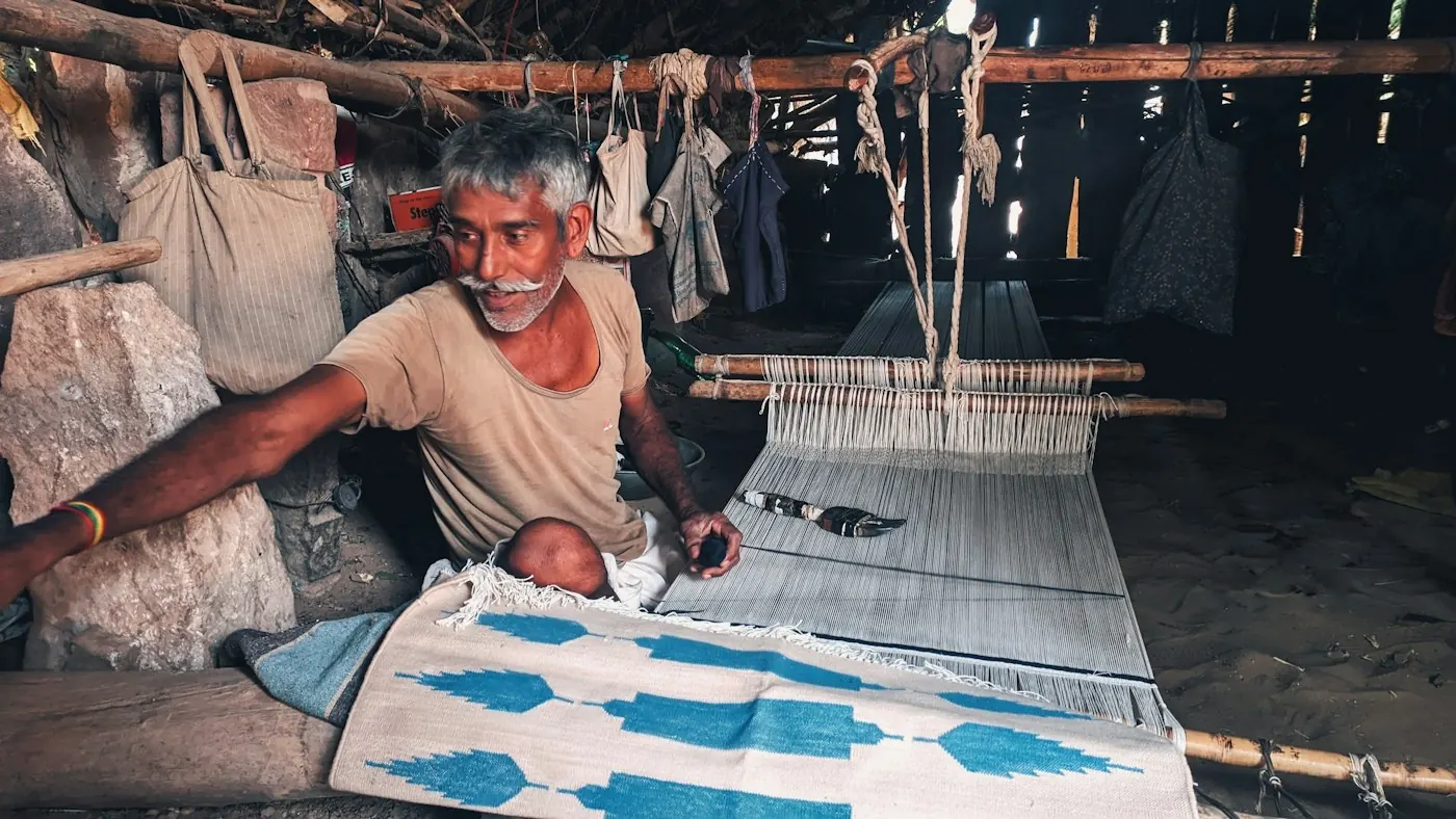 Weaver working on a patterned rug on a wooden loom in India